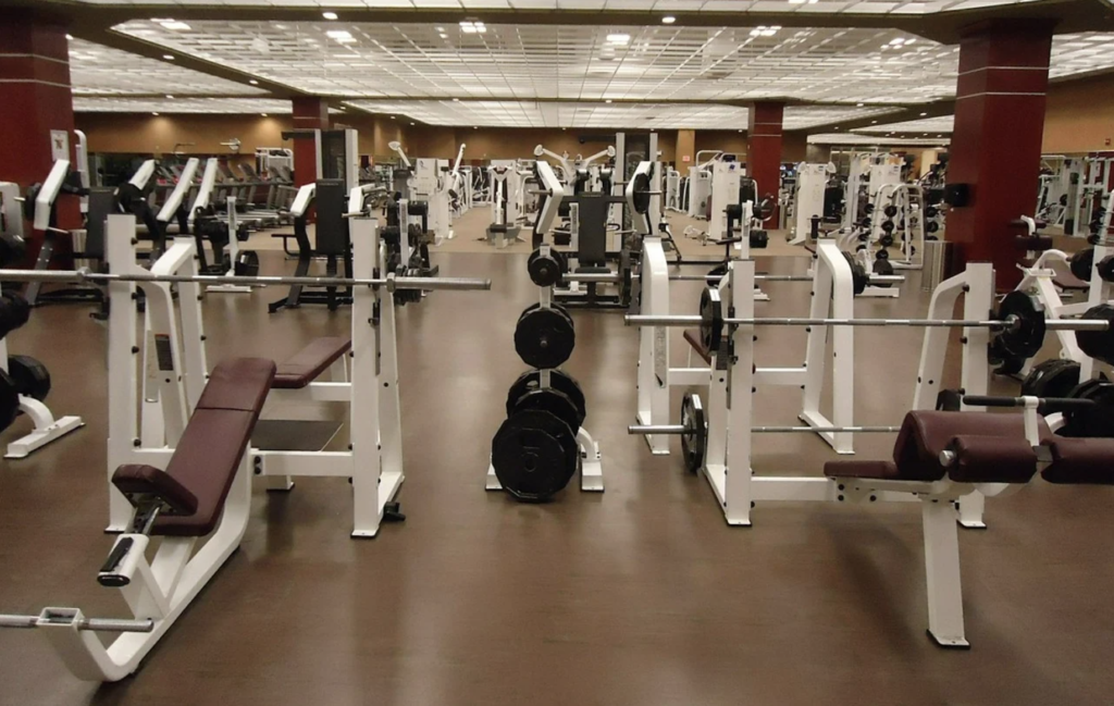 A view of a weight room in the gym with equipment from front to back. 