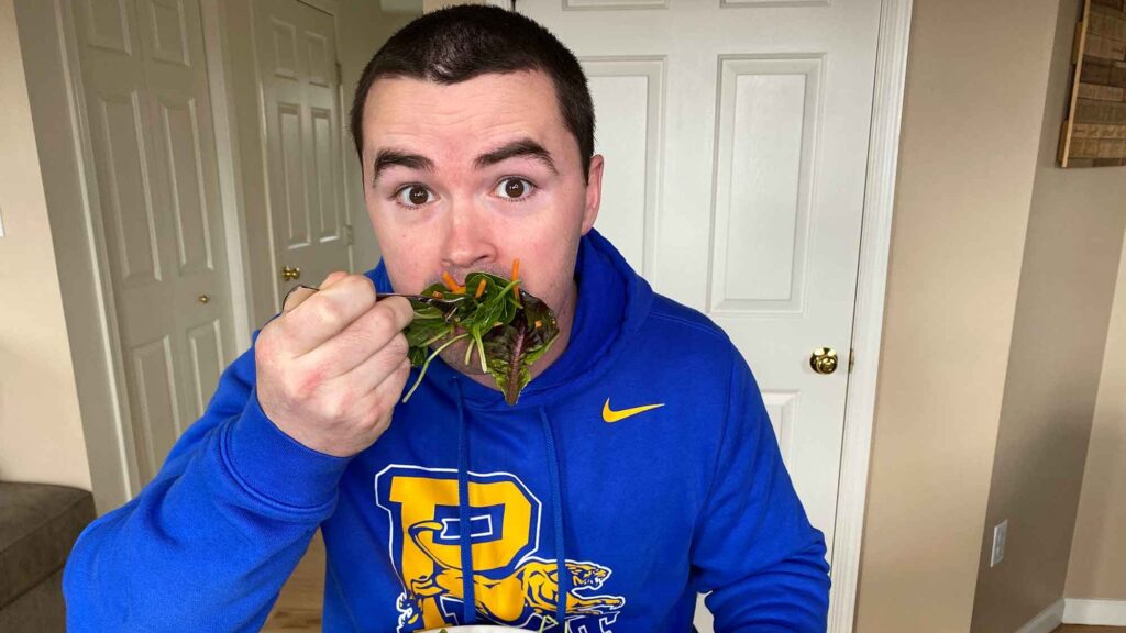 Chris Gates eating a large bit of salad